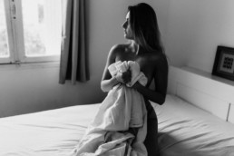 femme assise sur le lit, toute nue qui tiens un drap blanc contre elle