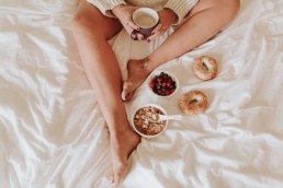 photo instagram femme dans son lit avec petit déjeuner. tatouage map monde sur le pied