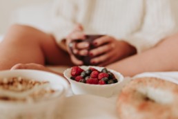 framboises fraiches avec myrtilles dans une tasse. Femme qui tiens un mug derrière