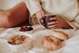femme qui tiens sa tasse de thé, avec bols de fruits rouges et céréales. Vernis rouge aux mains
