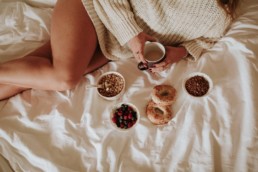 femme allongée sur le lit avec petit déjeuner et chai latte à la main