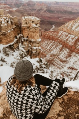 femme assise en haut du grand canyon sous la neige