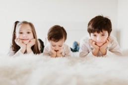 trois enfants sur le lit sur le ventre appuyés sur leurs mains à saint jean de védas