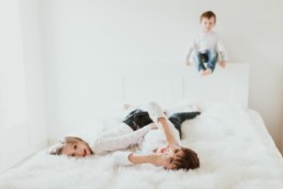 des enfants qui jouent sur le lit et font des grimaces à clapiers pour une séance photo