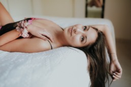 photo d'une belle femme brune aux cheveux longs allongés sur le lit, les bras qui tombent par dessus la tête