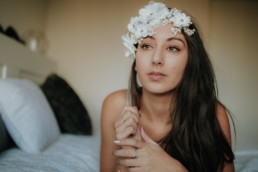 portrait femme brune fleurs blanches sur le front, qui réfléchi