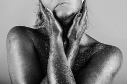 photo noir et blanc d une femme bras croisés sur le coup, la peau avec des paillettes
