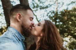 bisous sur la bouche pour un couple avec barbu, et chemise en jean, dans la nature à montpellier