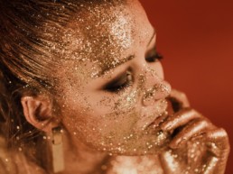 femme blonde recouverte de paillettes, maquillage des yeux smocky marron et noir, piercing au nez