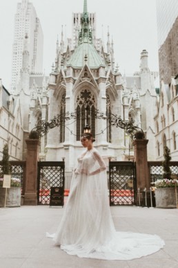 robe de mariage a paillette avec une longue cape devant une église a new york