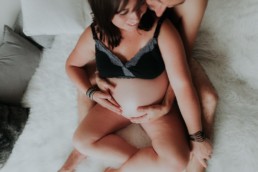 vue sur le ventre de femme enceinte avec le papa assis sur le lit, coussin gris