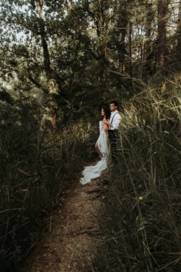 couple de mariés dans la forêt, robe de mariage en soie et longue traine