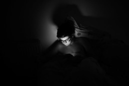 photo d'un adolescent dans sa chambre la nuit qui joue sur son téléphone