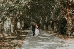 couple de mariés qui marchent sous les platanes à Gordes, apres la cérémonie laïque en plein air
