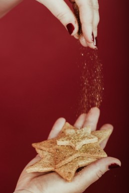 saupoudrer des paillettes sur des petits sablés de noel en forme d'étoile. Pâtisserie à Lattes, près de Montpellier