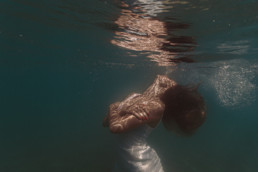 photo subaquatique portrait femme sous l'eau à la plage de aigues-mortes. Cheveux mouvement dan l'eau, bulles qui remontent à la surface, reflet portrait à la surface de l'eau