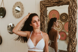 photo femme brune à la paillote bikinis beach de la grande motte, en maillot de bain blanc devant un miroir